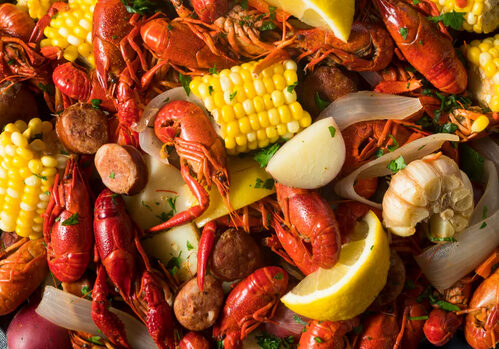 A close up of some crawfish, corn and lemon.