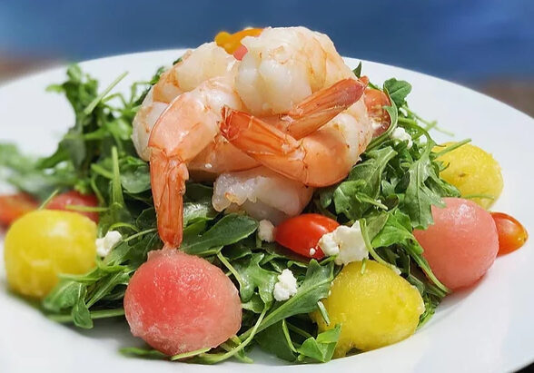 A salad with shrimp and watermelon on top.