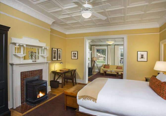 A bedroom with yellow walls and white bedding.