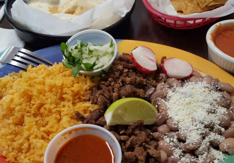 A plate of food with rice, meat and vegetables.