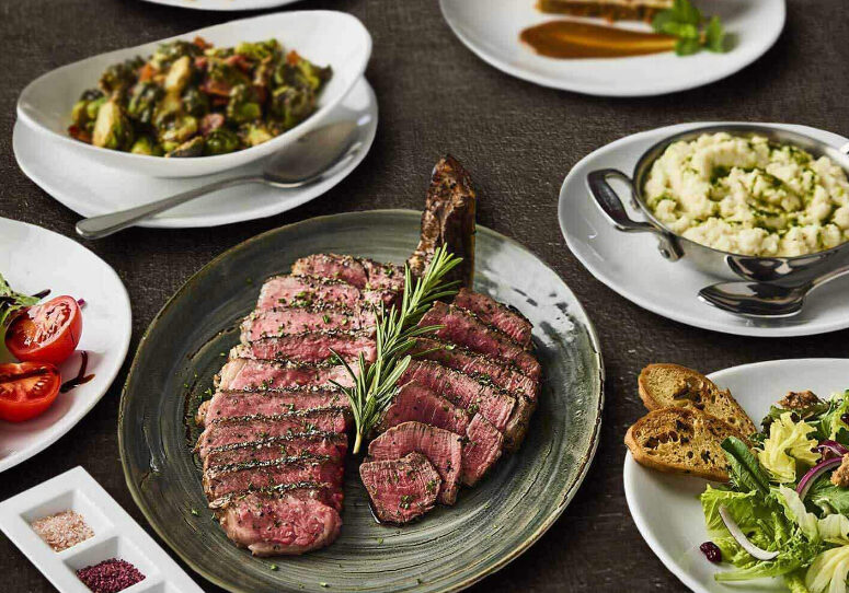 A plate of steak and other food on the table.