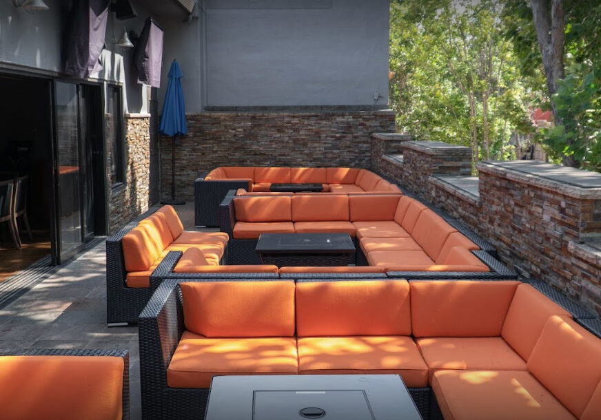 Fuego Sports Bar & Club A patio with orange couches and tables outside.