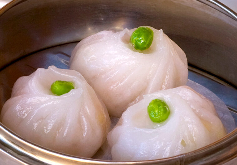 Three dumplings with green beans in a bowl.