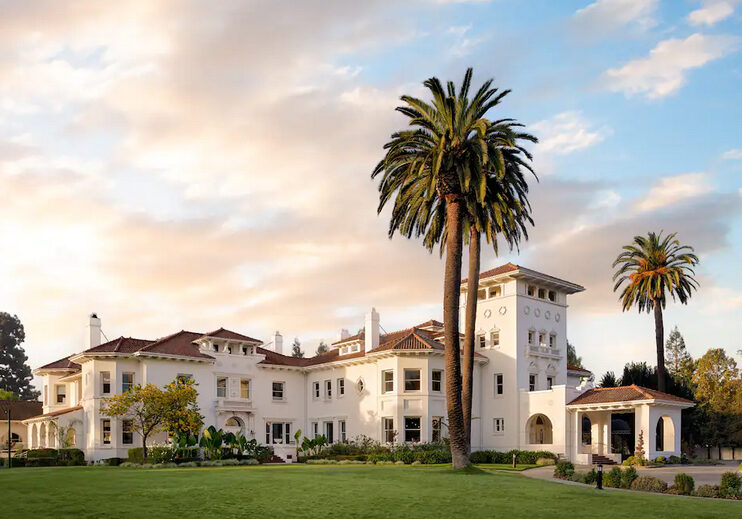 A large white building with palm trees in front of it.