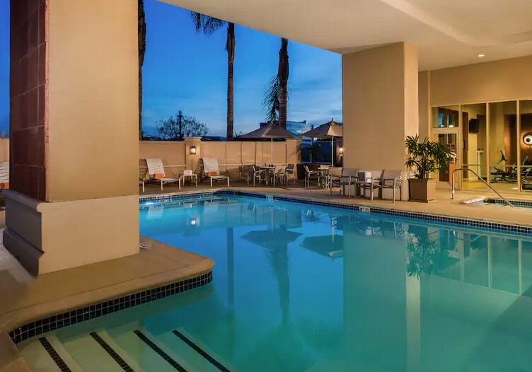 A pool with a view of the sky and palm trees.