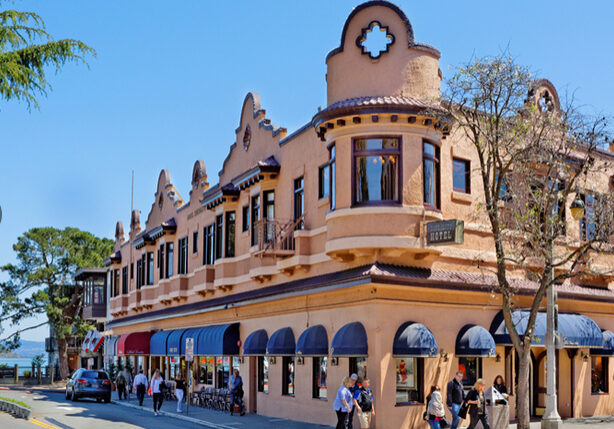 A building with many people walking on the sidewalk.