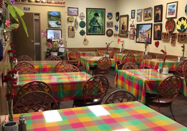 A restaurant with tables and chairs covered in colorful tablecloths.