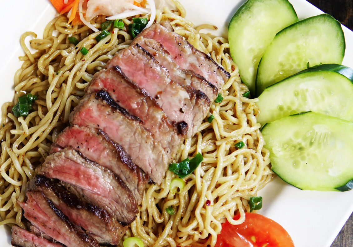 A plate of noodles with meat and vegetables.