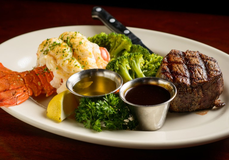 A plate of food with meat, broccoli and lobster.