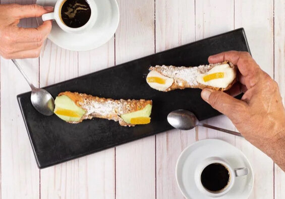 Sweet Sicily Italian Restaurant A person is holding some food on top of a table
