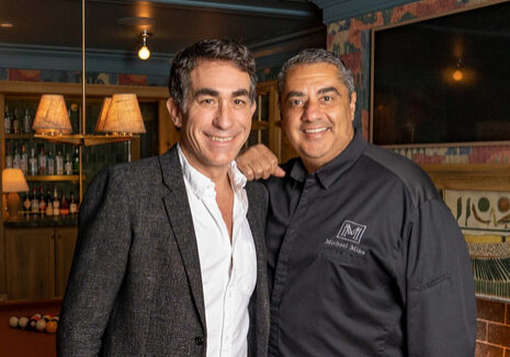 Two men posing for a picture in front of a bar.