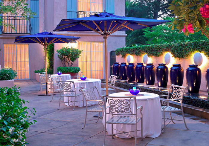 A patio with tables and chairs, blue umbrellas