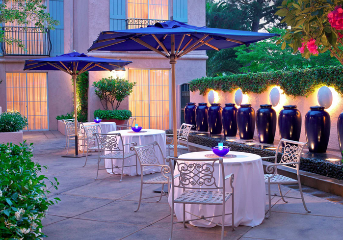 A patio with tables and chairs, blue umbrellas.