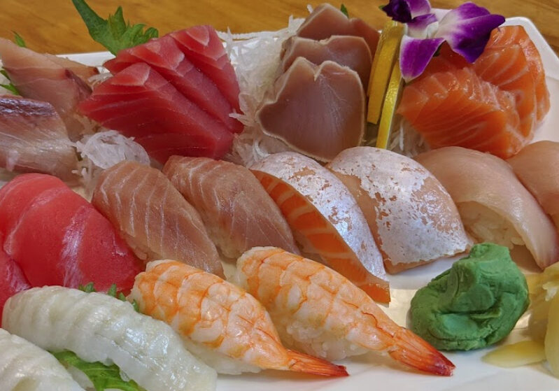 A plate of sushi and other food on the table.